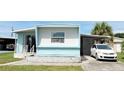 Single-story home with blue and white exterior with a lush lawn and a car parked in the driveway at 5233 Kenwood Ave, Sarasota, FL 34234