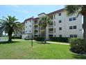 Exterior of a condo building with a red roof, green lawn, mature trees, and well-kept landscaping at 925 Beach Rd # 408, Sarasota, FL 34242