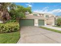 Townhouse with two-car garage, green doors, and lush landscaping framing the driveway and facade at 2303 28Th E Ave, Palmetto, FL 34221