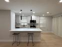 Modern kitchen with white cabinets, stainless steel appliances, quartz countertops, and bar seating at 4661 Linwood St, Sarasota, FL 34232