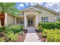 Attractive home entrance featuring a columned porch, decorative trim, and tropical landscaping at 6644 Butlers Crest Dr, Bradenton, FL 34203