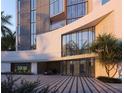 Elegant condo building entrance with a porte-cochere, lush landscaping, and modern architectural details at 688 Golden Gate Point # 202, Sarasota, FL 34236