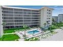 Beachfront condo building featuring a pool, lush landscaping, and screened balconies for enjoying ocean breezes at 1150 Tarpon Center Dr # 1-C 103, Venice, FL 34285