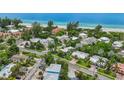 A beautiful aerial view of homes near a pristine beach, surrounded by lush trees and clear blue water at 202 75Th St, Holmes Beach, FL 34217