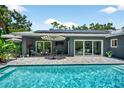 Inviting backyard pool area with a paved patio, outdoor seating, solar panels, and tropical landscaping at 2460 Hillview St, Sarasota, FL 34239