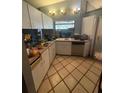 Compact kitchen featuring white cabinets, tile floor, and essential appliances at 303 70Th Nw St, Bradenton, FL 34209