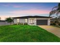 Charming one-story home featuring a manicured lawn and lush landscaping at dusk at 4314 Des Plaines Dr, Sarasota, FL 34233