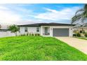 Charming one-story home with manicured lawn, gray garage door, and lush tropical landscaping at 4314 Des Plaines Dr, Sarasota, FL 34233