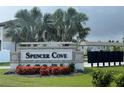 Community sign for Spencer Cove, landscaped with green grass and colorful red flowers at 5812 Ocean Isle Dr, Nokomis, FL 34275