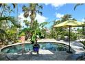 A backyard pool is surrounded by lush landscaping and a stone patio under a sunny sky, creating a private oasis at 701 Marbury Lane, Longboat Key, FL 34228
