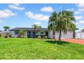 Well-maintained home with a spacious front yard, mature palm trees, and a blue front door at 8001 13Th S Ave, St Petersburg, FL 33707