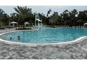 A large community pool featuring a splash pad, lounge chairs, and shady cabanas at 9291 Starry Night Ave, Sarasota, FL 34241