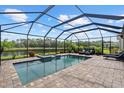 Backyard pool offers a covered spa, brick patio, and views of a tranquil lake at 11550 Blackfin St, Venice, FL 34292