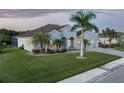 Beautifully landscaped home featuring a paver driveway, a three-car garage, and mature palms in a serene setting at 15808 42Nd E Gln, Parrish, FL 34219