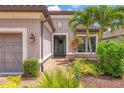 Close up view of the front of a home featuring a welcoming front door and lush tropical landscaping at 5596 Cantucci St, Nokomis, FL 34275