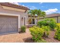 Close up view of the front of a home featuring a brick driveway and lush tropical landscaping at 5596 Cantucci St, Nokomis, FL 34275