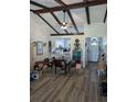 Open-concept living room featuring vaulted ceilings, wooden beams, and views of the kitchen and front entrance at 5231 Brassy Loop, North Port, FL 34287