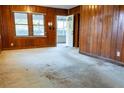 Bright living room featuring wood paneled walls, carpet, and a doorway to the screened porch at 126 W North St, Tampa, FL 33604