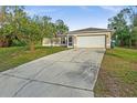 Tan one-story house with a long driveway and attached garage at 1340 Papillon St, North Port, FL 34287