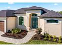 Home exterior featuring teal front door and landscaping at 9437 Galaxie Cir, Port Charlotte, FL 33981