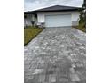 A home with a two-car garage featuring a decorative paver driveway and manicured landscaping at 8285 Agate St, Port Charlotte, FL 33981