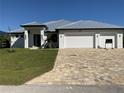 Modern house exterior with white walls, gray metal roof, and a large driveway at 13654 Allamanda Cir, Port Charlotte, FL 33981
