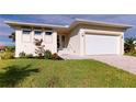 Single-story home with light-colored exterior, white garage door, and landscaped yard at 17007 Ginger Ln, Punta Gorda, FL 33955