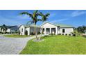 Single-story home with a green metal roof, palm trees, and a paved driveway at 2033 Treasure Ln, Punta Gorda, FL 33982