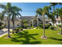 Charming single-story home featuring a well-manicured lawn, lush landscaping, and beautiful palm trees at 2505 Rio Tiber Dr, Punta Gorda, FL 33950