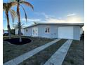 Inviting home featuring a long driveway, one car garage and tropical landscaping with palm trees at 4127 Gardner Dr, Port Charlotte, FL 33952