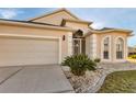 Beige house with a two-car garage, landscaping, and a walkway at 1712 Lastingham Ln, Port Charlotte, FL 33980
