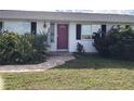 Front view of a white house with red door and landscaping at 21277 Edgewater Dr, Port Charlotte, FL 33952