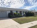 Front view of white house with red door and landscaping at 21277 Edgewater Dr, Port Charlotte, FL 33952