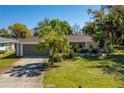 Charming single-story home featuring a well-maintained lawn, mature palm trees, and an attached two car garage at 1150 Winston St, Port Charlotte, FL 33952
