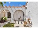 Elegant entryway with arched walkways, white stucco walls, and tropical plants at 5081 San Rocco Ct, Punta Gorda, FL 33950