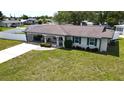 Single-story home with a white brick facade, teal accents, and a well-manicured lawn at 22260 Aburto Ln, Port Charlotte, FL 33952