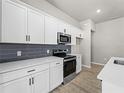Modern kitchen with white cabinets, gray tile backsplash and quartz countertops at 1417 Longson St, Port Charlotte, FL 33953