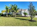 New construction home with two-car garage, lush landscaping, and palm trees at 14436 Ponce De Leon Trl, Port Charlotte, FL 33981