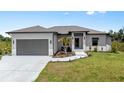 Single-story home with gray garage door and landscaping at 13552 Boatbill Ln, Port Charlotte, FL 33981