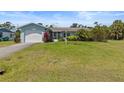 Light blue single story house with a large yard and attached garage at 1585 Harmony Dr, Port Charlotte, FL 33952