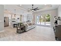 Spacious living room featuring wood-look tile flooring, a modern fan, and sliding glass doors to the lanai at 13348 Rayburn Ln, Port Charlotte, FL 33981
