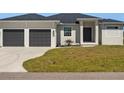 White two-car garage home with dark gray garage doors and landscaping at 13348 Rayburn Ln, Port Charlotte, FL 33981