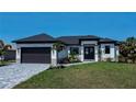 Stunning curb appeal! This new home features a modern design, dark gray garage door, and beautifully landscaped lawn at 11 Pinehurst Ct, Rotonda West, FL 33947