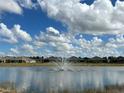 Scenic pond view with a fountain and houses under a partly cloudy sky creates a peaceful community setting at 7168 W Lenox Cir, Punta Gorda, FL 33950