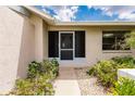 Front entrance with a screened door and flowering plants at 3621 Whippoorwill Blvd, Punta Gorda, FL 33950
