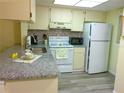 Cozy kitchen featuring tile backsplash, white appliances, and granite countertops at 25275 Rampart Blvd # 2001, Punta Gorda, FL 33983