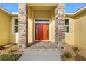Inviting front entrance with a vibrant orange door, stone accents, and manicured landscaping at 16077 Coruna Ct, Punta Gorda, FL 33955