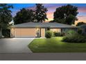 Charming home at twilight featuring a metal roof, well-manicured lawn, and beautiful flowering shrubbery at 23117 Hillsdale Ave, Port Charlotte, FL 33954