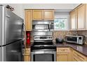 Galley kitchen featuring stainless steel appliances and light wood cabinets at 22375 Edgewater Dr # 126, Port Charlotte, FL 33980