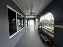Enclosed porch featuring gray floors, a ceiling fan, and windows looking out onto the front yard, providing a cozy outdoor space at 1405 Dorchester St, Port Charlotte, FL 33952
